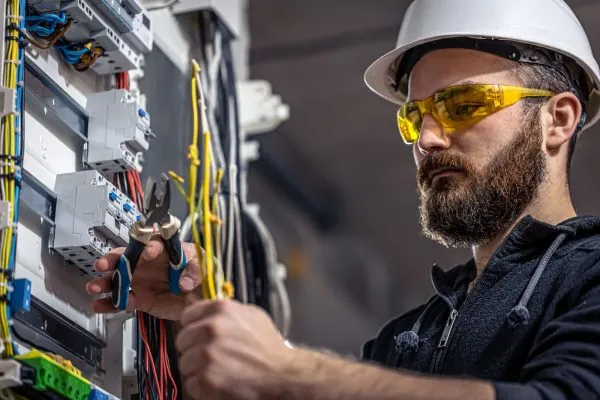 Eletricista avaliando quadro elétrico de empresa